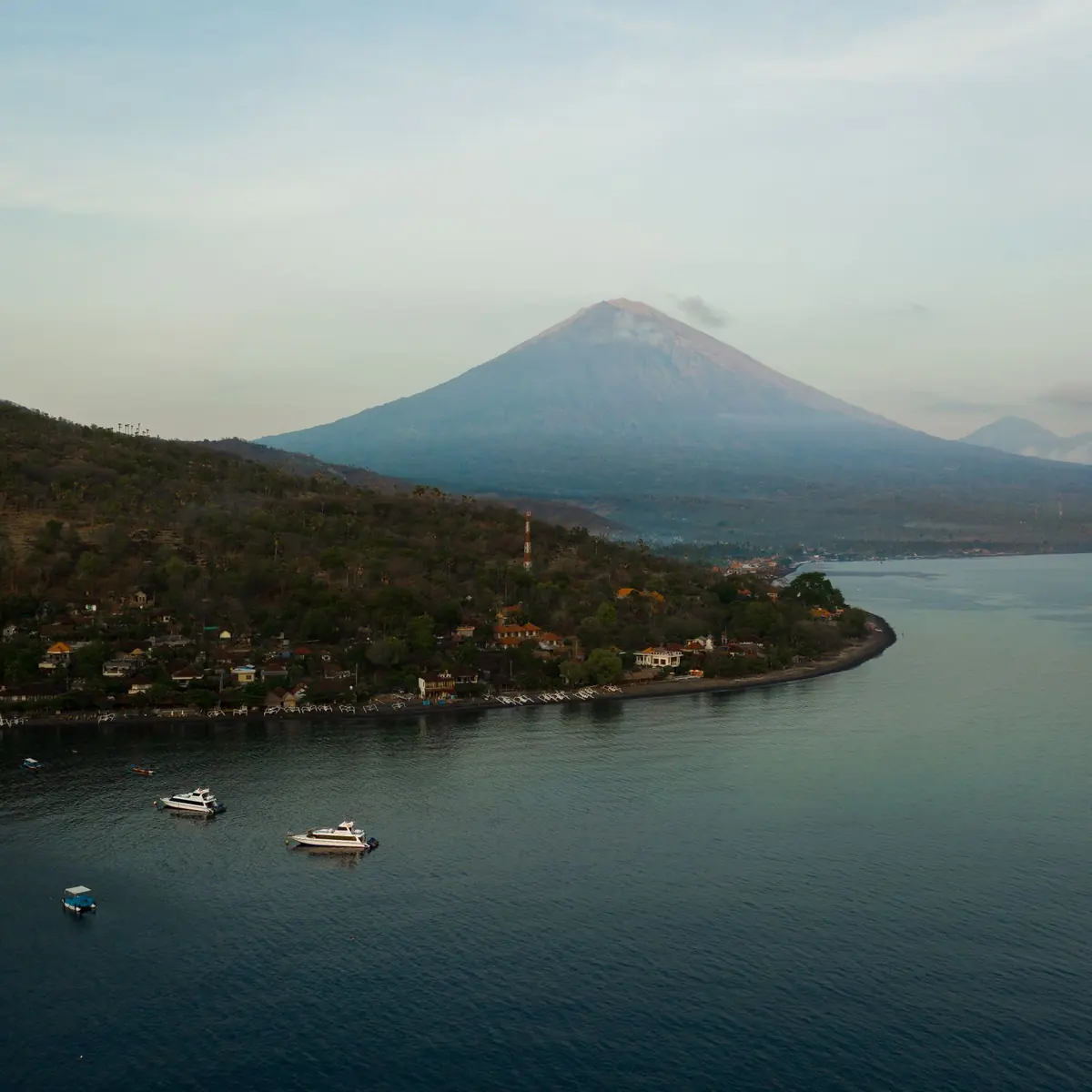 Aerial view of a calm bay on the Amed coast with Mount Agung in the distance
