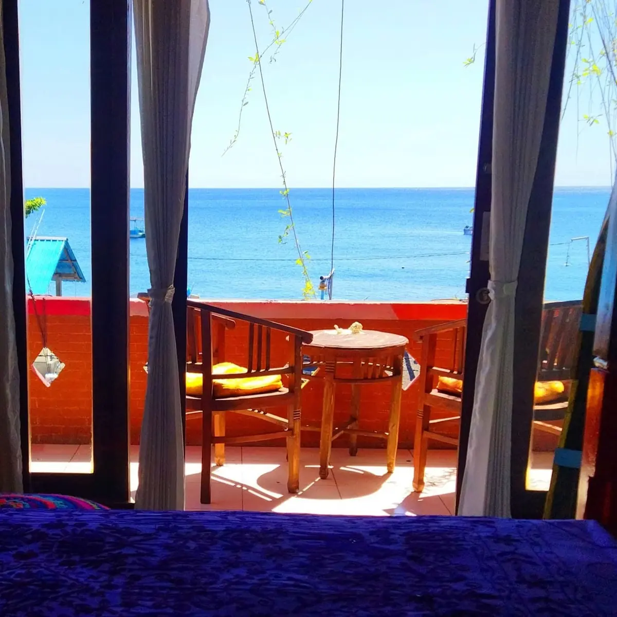 The view from a Pelangi balcony: two chairs, a small table and the sea beyond